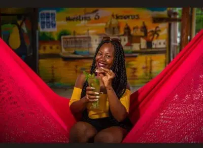 a woman sitting in a hammock holding a drink at TESORO de BARU in Cartagena de Indias