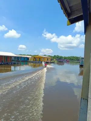 a boat on a river with houses on the shore at Laguna tour in Nueva Venecia