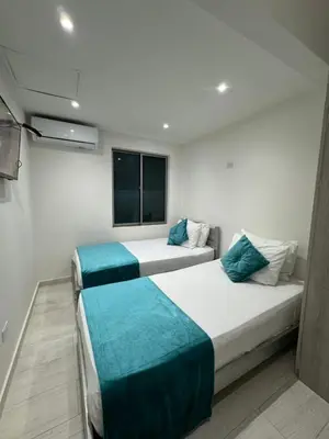 two beds in a small room with a window at Apartamentos Crespo 67 aeropuerto in Cartagena de Indias
