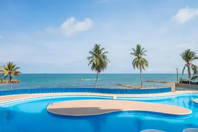 a swimming pool with palm trees and the ocean at Hermoso Apartamento Frente al Mar 2 Habitaciones PAZ146 in Coveñitas