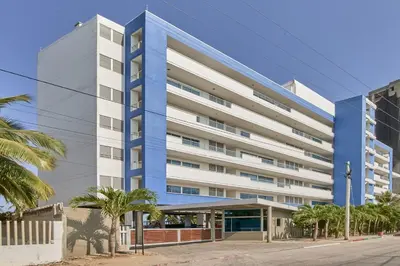 a blue and white building on a street with palm trees at Hermoso Apartamento Frente al Mar 2 Habitaciones PAZ146 in Coveñitas