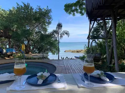 a table with two glasses of wine and the ocean at COCO SALVAJE Tree House in La Rada