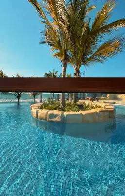 a swimming pool with a palm tree in the background at Un paraíso frente al mar in San Silvestre