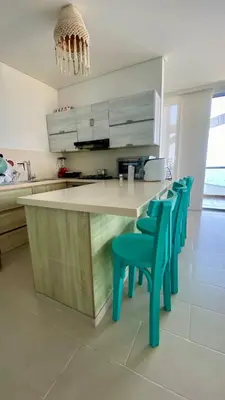 a kitchen with a counter with blue chairs in it at Fontainebleu in Coveñas