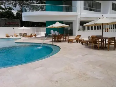 a swimming pool with tables and chairs and umbrellas at Fontainebleu in Coveñas
