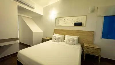 a bedroom with a white bed with two pillows at Auaecoco Hotel in Cartagena de Indias