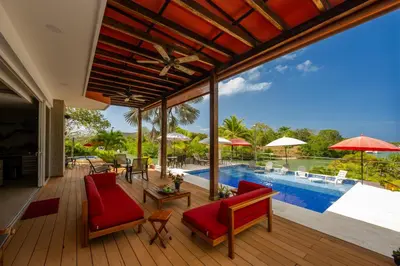 an open deck with red chairs and a swimming pool at Maravillosa Villa en Marina Baru enCartagena! in Isla Barú