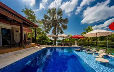 a pool with chairs and umbrellas next to a house at Maravillosa Villa en Marina Baru enCartagena! in Isla Barú
