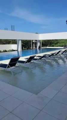 a swimming pool with lounge chairs and a table at Aparta suite cerca al mar por vía Irotama in Santa Marta
