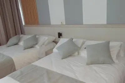 two beds in a room with white sheets and pillows at Aparta suite cerca al mar por vía Irotama in Santa Marta
