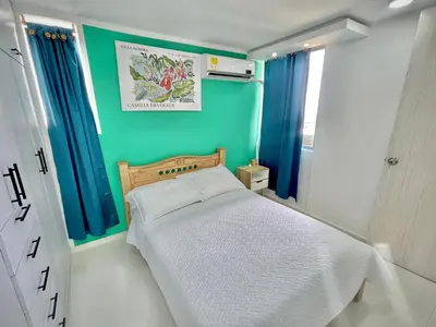 a small bedroom with a bed with a green wall at Apartamento con vista única cerca de la Uninorte in Puerto Colombia
