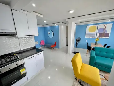 a kitchen and living room with blue walls and a yellow chair at Apartamento con vista única cerca de la Uninorte in Puerto Colombia