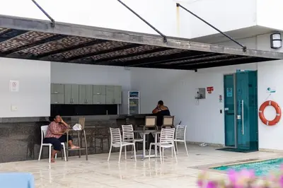 a couple of people sitting at a table in a building at Majestic apt with an ocean view Palmetto Beach in Cartagena de Indias