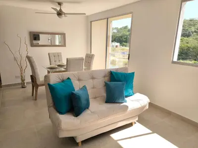 a living room with a white couch with blue pillows at Tu refugio perfecto in Manzanillo del Mar