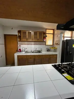 a kitchen with wooden cabinets and a black refrigerator at Hostal Tayrona in Santa Marta