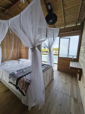 a bedroom with a bed with a mosquito net at Casa Acuarimantima in Tintipan Island