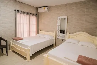 a bedroom with two beds and a chair and a mirror at Casa con piscina cerca al aeropuerto in Malambo