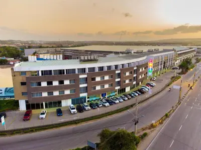 a large building with cars parked in a parking lot at Pop Art Hotel CLC Puerto Mamonal Cartagena in Cartagena de Indias