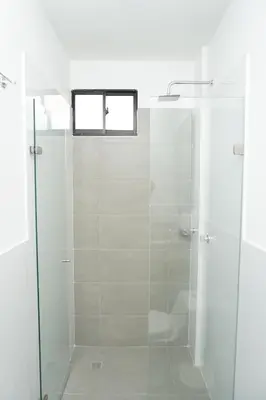 a shower with a glass door and a window at Hotel INdustrial in Sincelejo