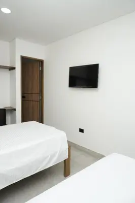a bedroom with two beds and a flat screen tv at Hotel INdustrial in Sincelejo
