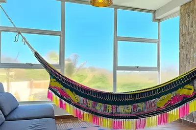 a hammock hanging in a living room with windows at Casa de playa privada Sabanilla 4 cuadras del mar in Maizal