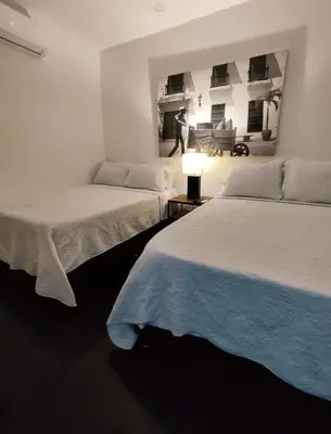 two beds in a white room with a man in the background at Apartamento en cartagena - cristoforo piso 7 in Cartagena de Indias