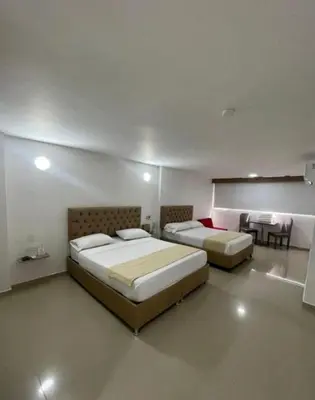 a room with two beds and a table and a kitchen at HS-C Habitación Cuádruple con aire acondicionado y piscina in Cartagena de Indias