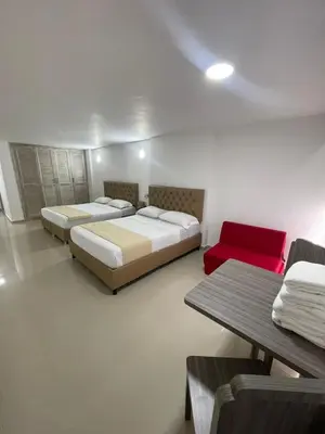 a bedroom with two beds and a red couch at HS-C Habitación Cuádruple con aire acondicionado y piscina in Cartagena de Indias
