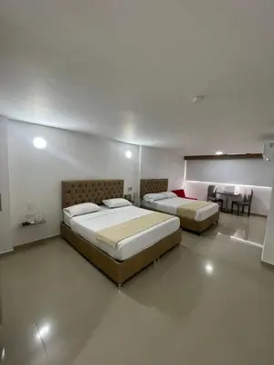 two beds in a large room with a table and chairs at HS-C Habitación Cuádruple con aire acondicionado y piscina in Cartagena de Indias