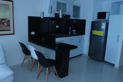 a kitchen with a black counter and chairs and a refrigerator at Arriendos S.H. Nuevo Conquistador in Cartagena de Indias