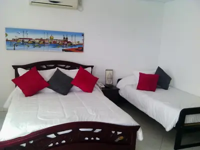 two beds with red and black pillows in a room at Arriendos S.H. Nuevo Conquistador in Cartagena de Indias