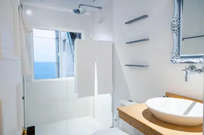 a white bathroom with a sink and a shower at Renovated with ocean view in historic center! in Cartagena de Indias