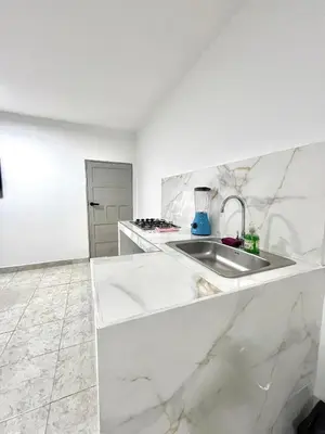 a white kitchen with a sink and a counter at Comfortable loft in Barranquilla in Barranquilla