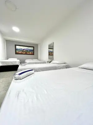 a row of white beds in a room at Comfortable loft in Barranquilla in Barranquilla