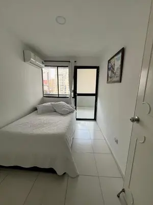 a white bedroom with a bed and a window at Portofino Apartments in Cartagena de Indias
