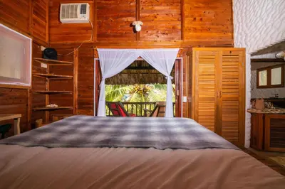 a bedroom with a bed and a window with a chair at Cabaña San Miguel in Moñitos