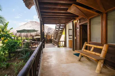 a porch of a resort with a bench and an umbrella at Cabaña San Miguel in Moñitos