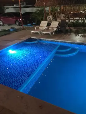 a blue swimming pool with two chairs and a car at Habitacion con piscina-jacuzzi-lavadora disponible in Juan de Acosta