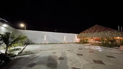 a building with a thatch roof and a building at night at Habitacion con piscina-jacuzzi-lavadora disponible in Juan de Acosta