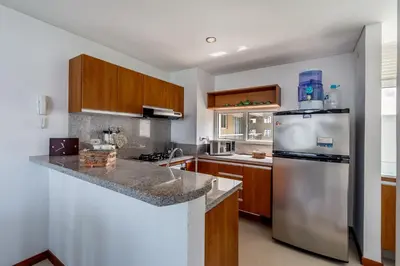 a kitchen with a stainless steel refrigerator and wooden cabinets at Apartamento con vista al mar - Condominio Zazué in Santa Marta