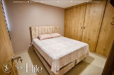 a bedroom with a bed and a wooden cabinet at Suite Elite Barranquilla in Barranquilla