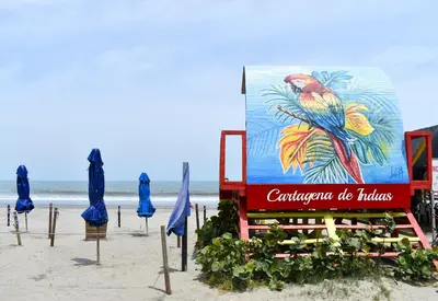 a sign on the beach with blue umbrellas at Comfortable apartment close to the beach 2 rooms in Cartagena de Indias