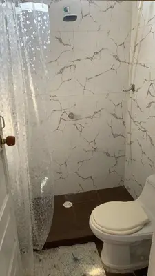 a white bathroom with a toilet and a shower at Apartamento Ciudad Jardin Barranquilla in Barranquilla