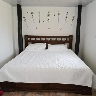 a bedroom with a bed with white sheets and skulls on the wall at Dulce Barú in Cartagena de Indias
