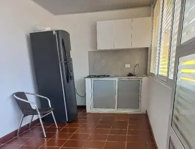 a kitchen with a refrigerator and a chair in a room at Dulce Barú in Cartagena de Indias