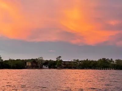 a sunset over a lake with houses and trees at Villa Luz Coastal Sanctuary in Tintipan Island