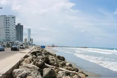 a beach with rocks and the ocean and buildings at comodo apto marbella b17 in Cartagena de Indias