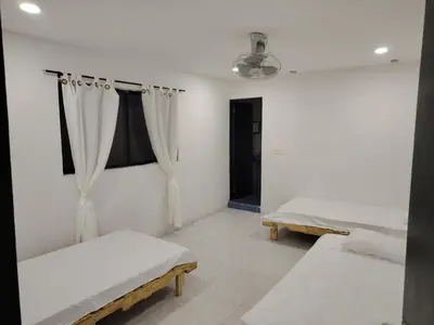 a white room with two beds and a window at Casa yamulemao in Cartagena de Indias