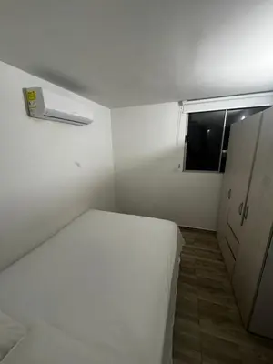 a small white room with a bed and a window at New & peaceful apartment in Barranquilla