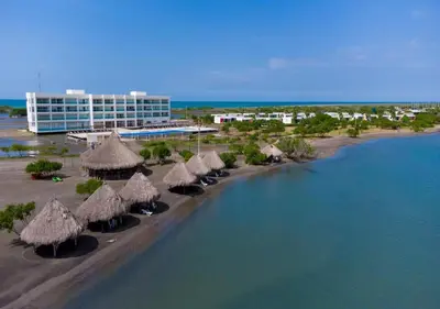 a beach with some straw umbrellas and a building at Marina Puerto Velero, Villa frente al Mar in El Morro